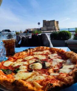 Estate a Napoli la pizza sul lungomare con vista sul castel dell'ovo